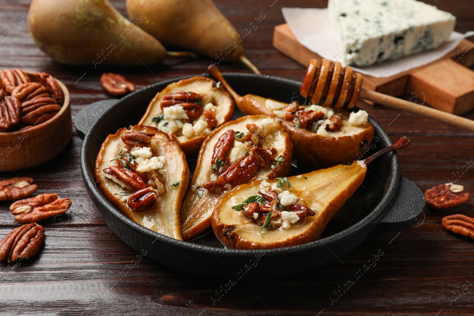 Photo of Delicious baked pears with nuts, blue cheese and honey on wooden table, closeup