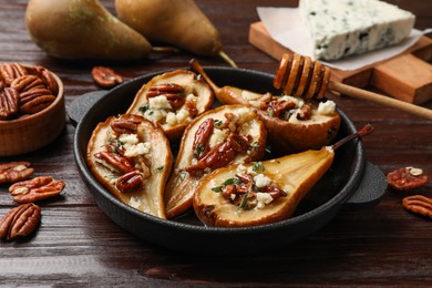 Delicious baked pears with nuts, blue cheese and honey on wooden table, closeup