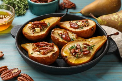 Photo of Delicious baked pears with nuts, blue cheese, thyme and honey on light blue wooden table, closeup