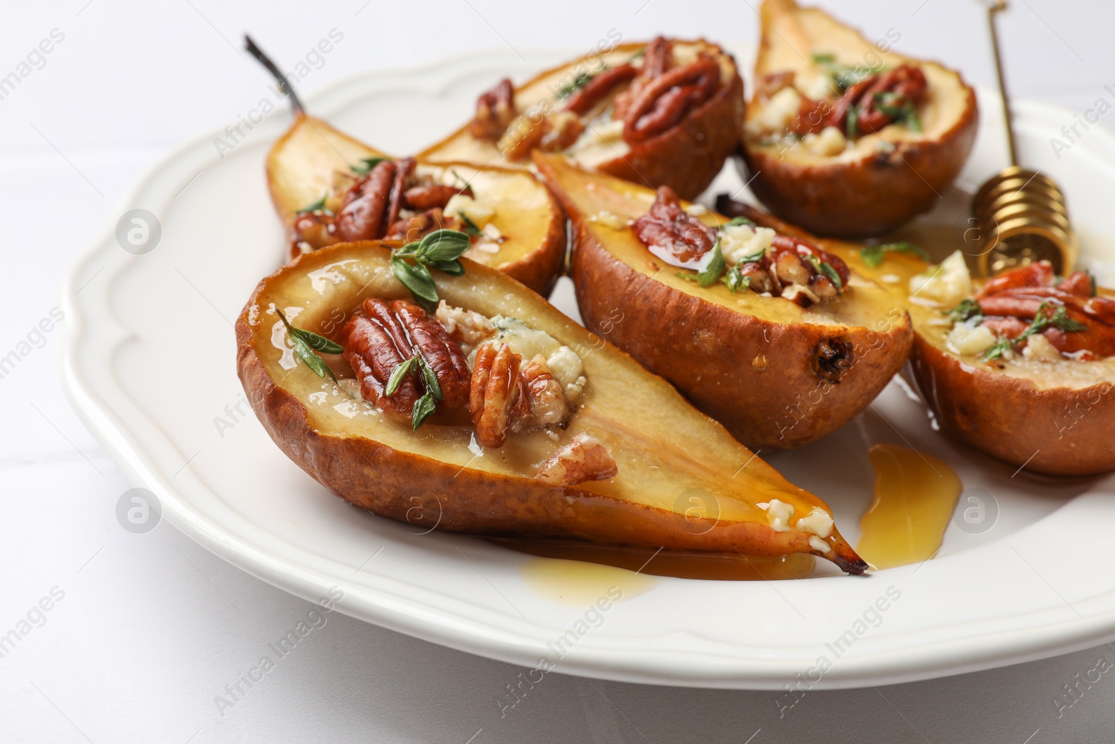 Photo of Delicious baked pears with nuts, blue cheese, thyme and honey on white table, closeup