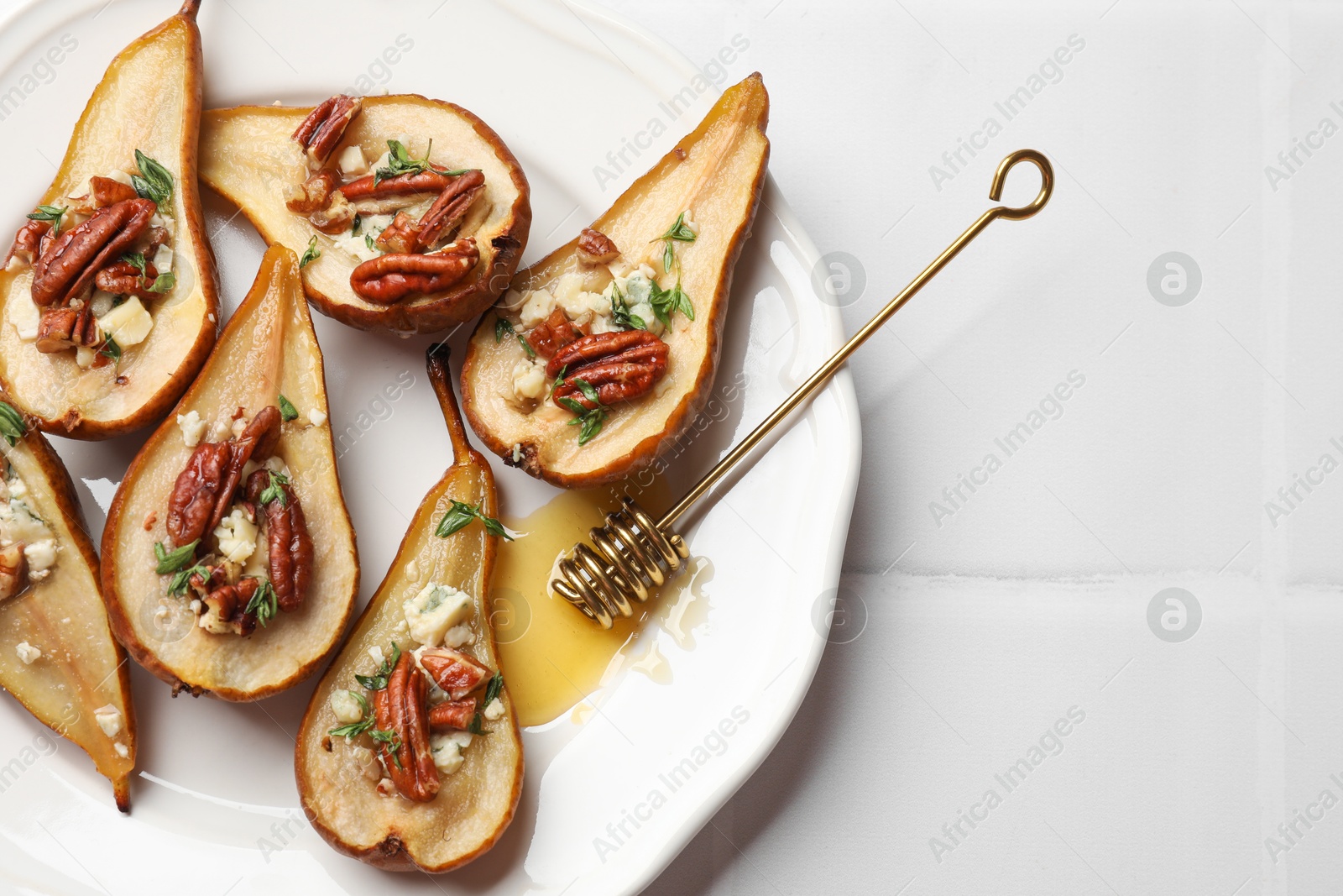 Photo of Delicious baked pears with nuts, blue cheese, thyme and honey on white tiled table, top view. Space for text