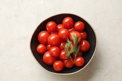 Photo of Tasty pickled tomatoes and dill in bowl on light grey table, top view