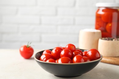 Tasty pickled tomatoes in bowl and spices on light grey table