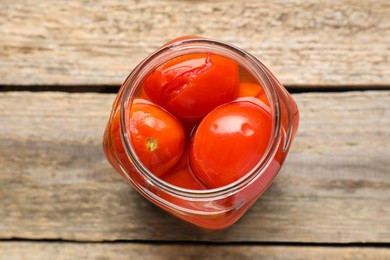 Photo of Tasty pickled tomatoes in jar on wooden table, top view