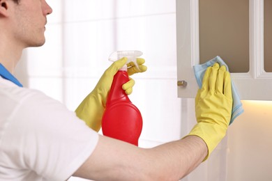 Photo of Professional janitor cleaning cabinet in kitchen, closeup