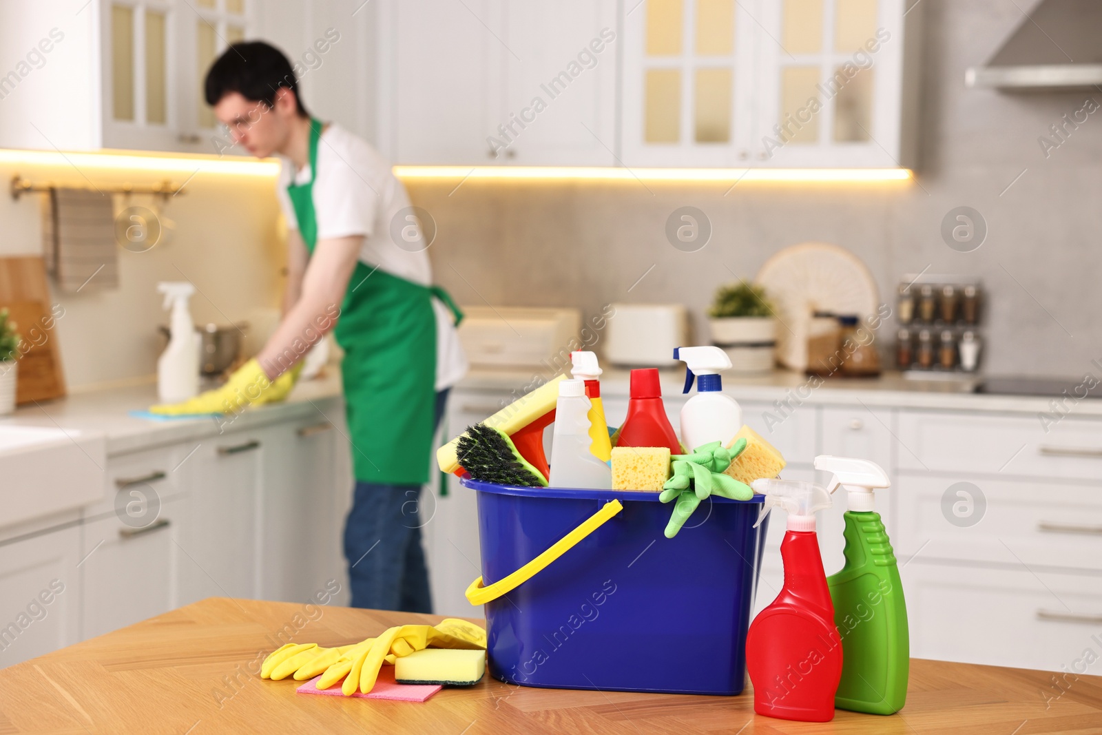 Photo of Professional janitor working in kitchen, focus on bucket with supplies. Cleaning service