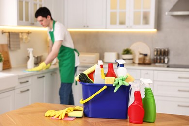 Professional janitor working in kitchen, focus on bucket with supplies. Cleaning service