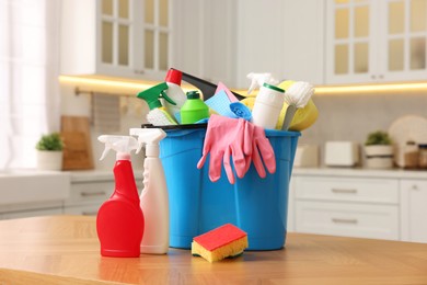 Photo of Cleaning service. Bucket with supplies on table in kitchen