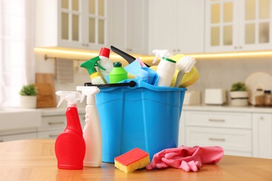 Photo of Cleaning service. Bucket with supplies on table in kitchen