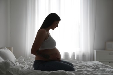 Photo of Beautiful pregnant woman on bed at home