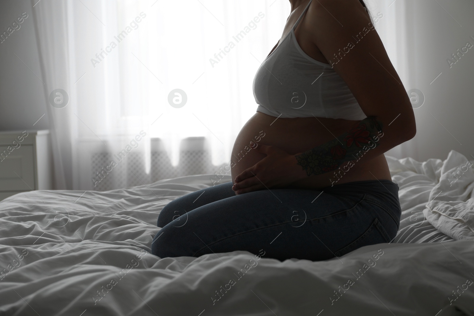 Photo of Beautiful pregnant woman on bed at home, closeup