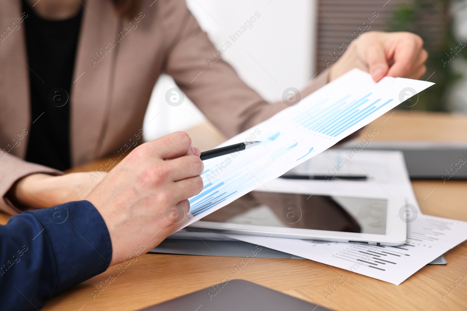 Photo of Consultant working with client at table in office, closeup