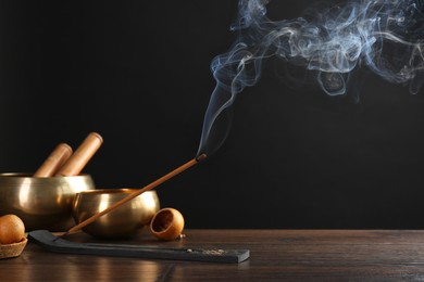 Photo of Aromatic incense stick smoldering on wooden table