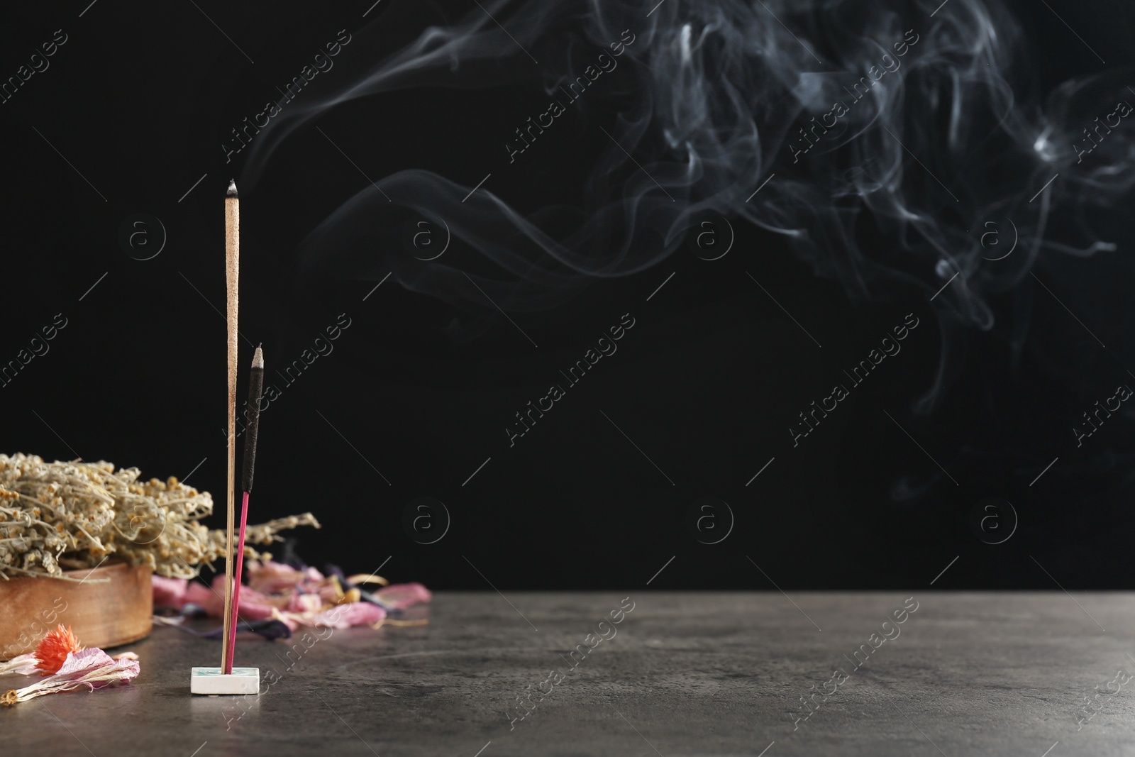 Photo of Aromatic incense sticks smoldering on grey table. Space for text