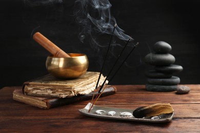 Photo of Aromatic incense sticks smoldering on wooden table