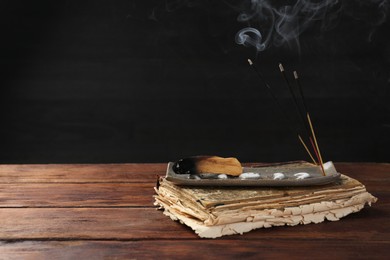 Photo of Aromatic incense sticks smoldering on wooden table. Space for text