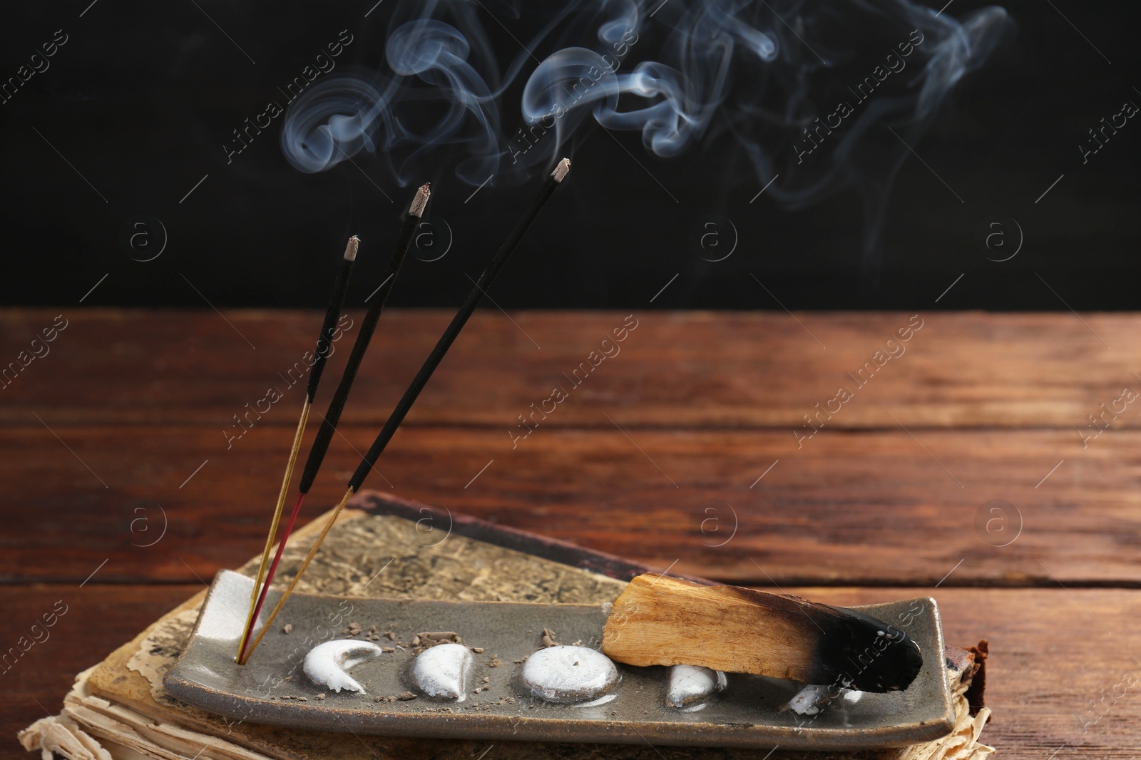 Photo of Aromatic incense sticks smoldering on wooden table, closeup. Space for text