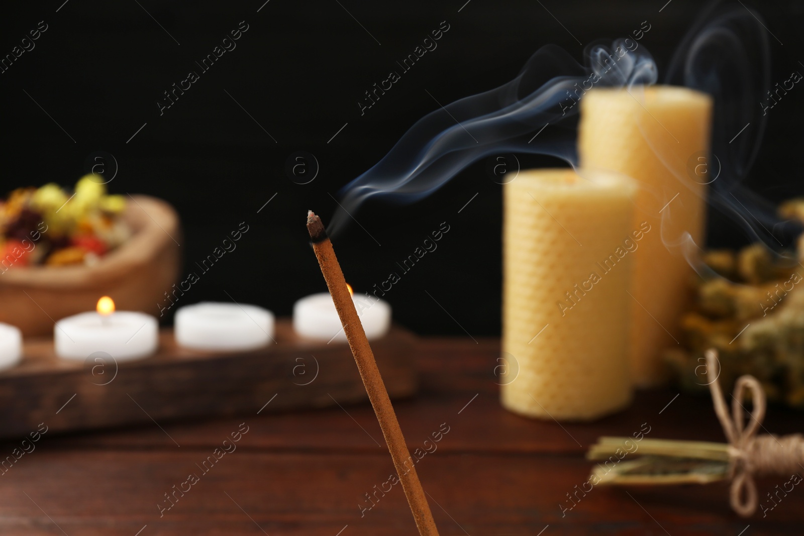 Photo of Aromatic incense stick smoldering on blurred background, closeup