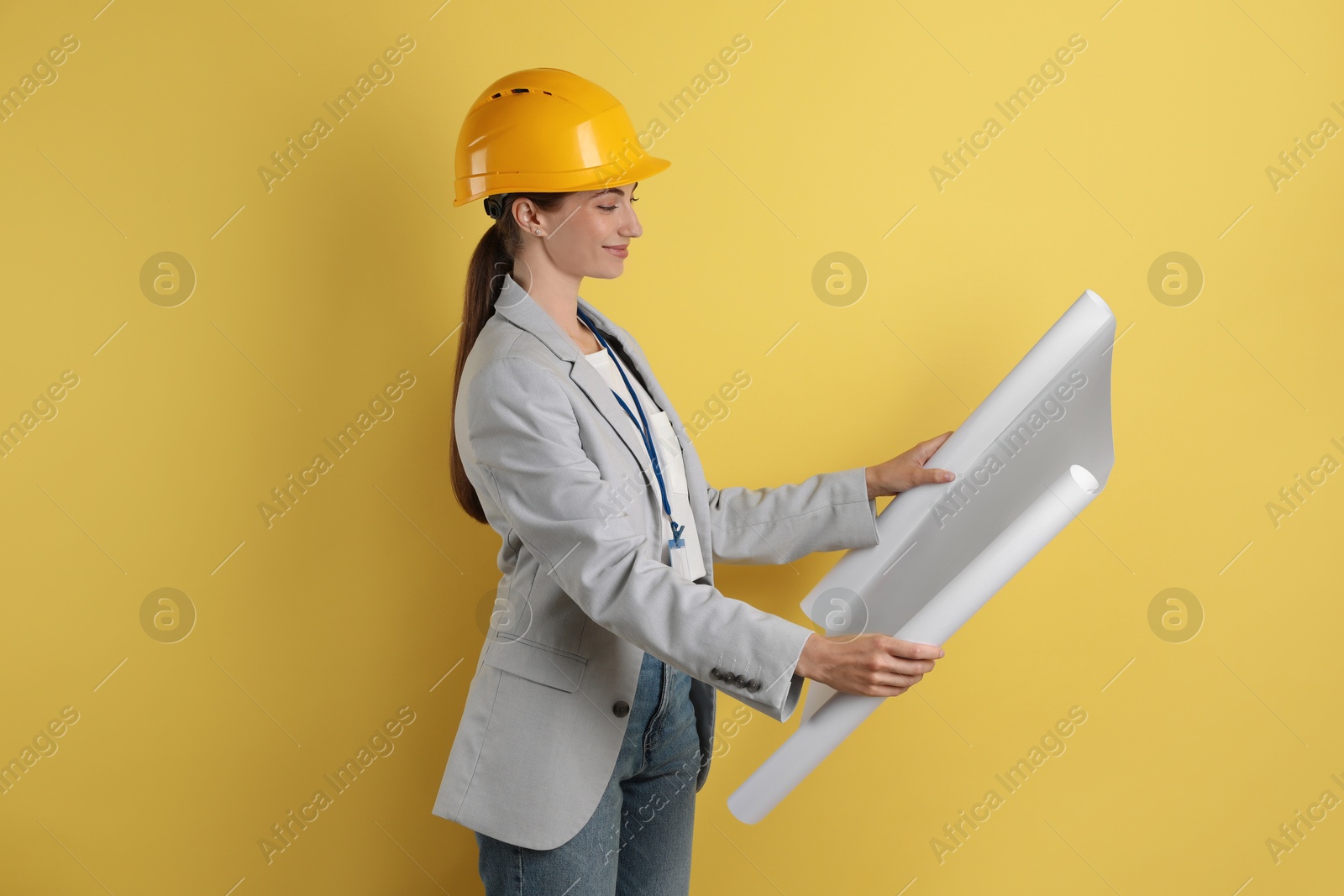 Photo of Engineer in hard hat with draft on yellow background