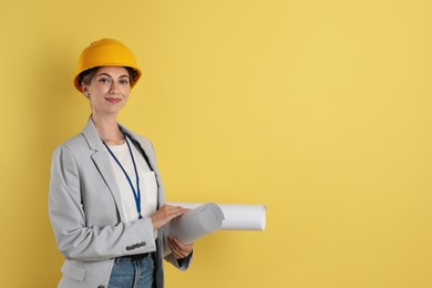 Photo of Engineer in hard hat with drafts on yellow background, space for text