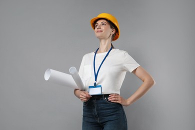 Photo of Engineer in hard hat with drafts on grey background, low angle view
