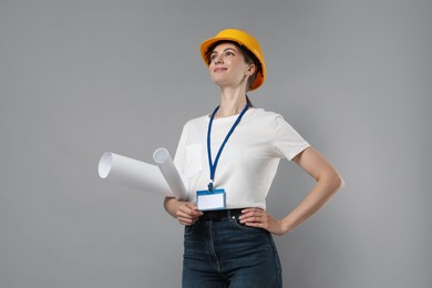 Engineer in hard hat with drafts on grey background, low angle view