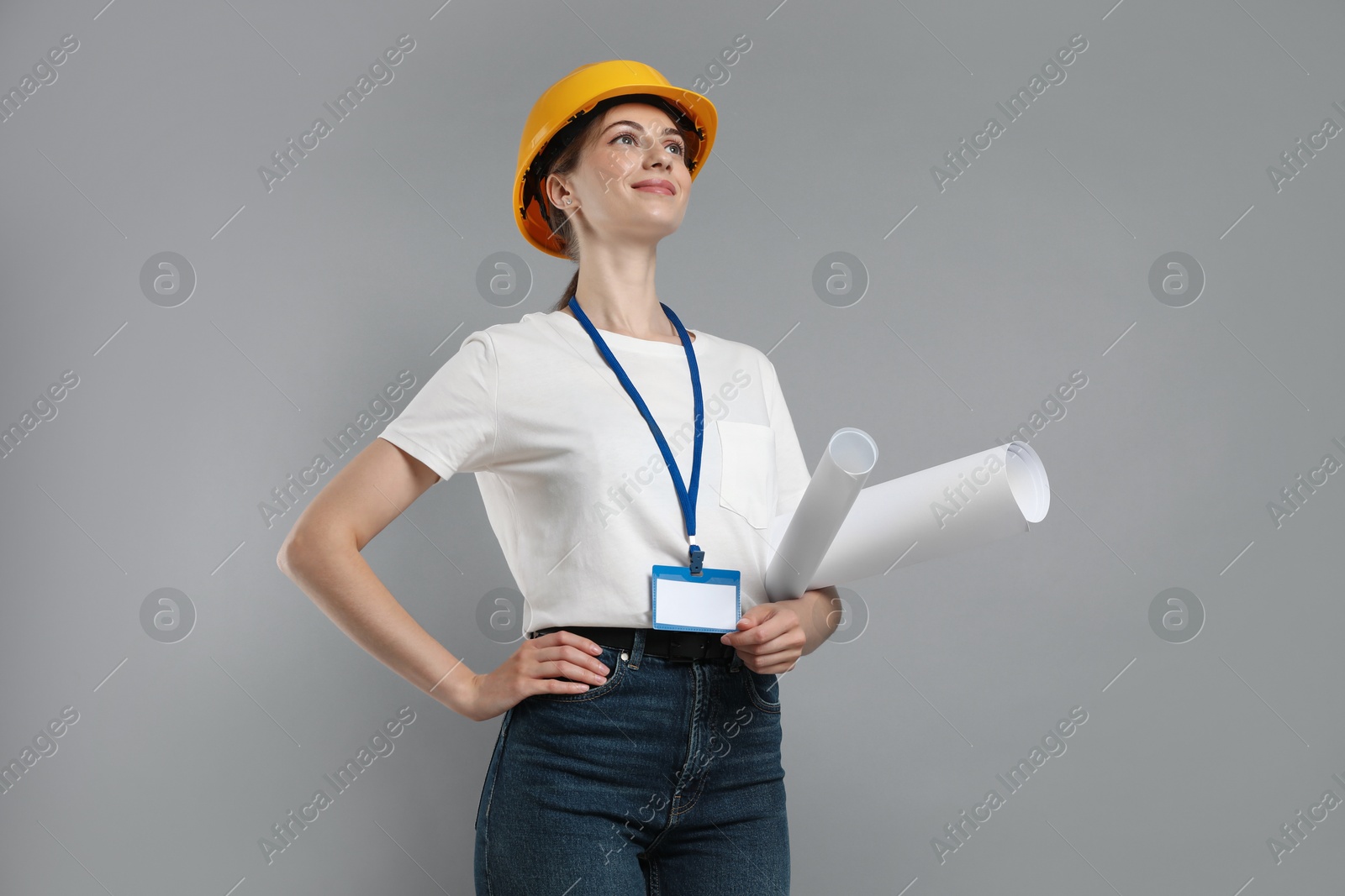 Photo of Engineer in hard hat with drafts on grey background, low angle view