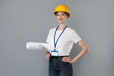 Engineer in hard hat with drafts on grey background