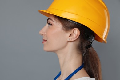 Engineer in hard hat on grey background, space for text