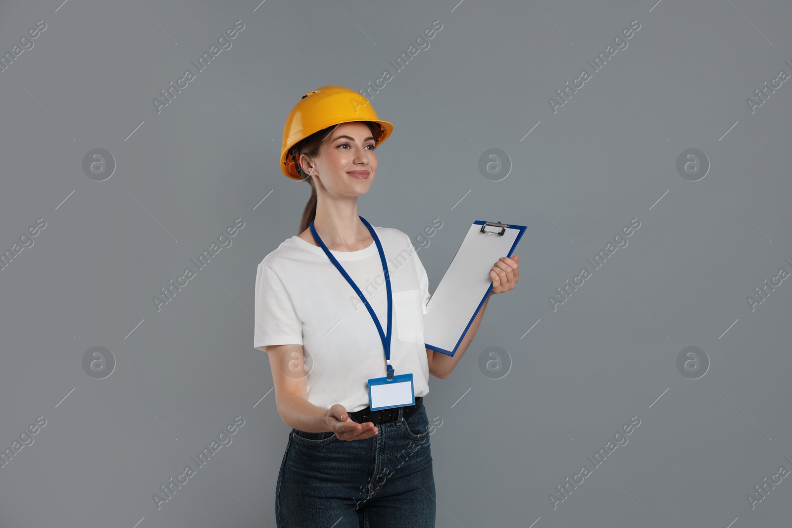 Photo of Engineer in hard hat with clipboard on grey background