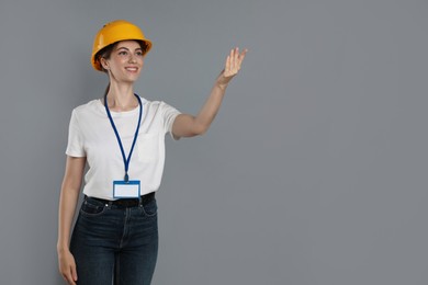 Engineer in hard hat on grey background, space for text