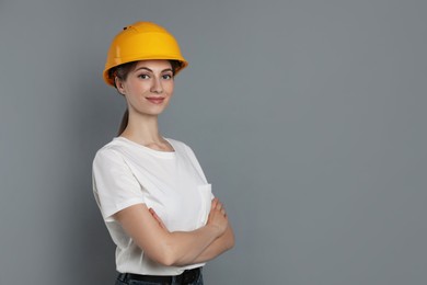 Engineer in hard hat on grey background, space for text