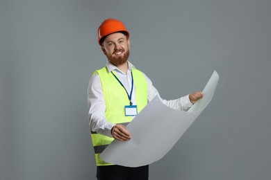 Engineer in hard hat with draft on grey background