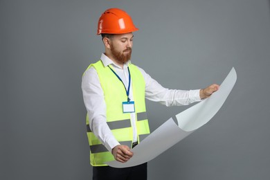 Photo of Engineer in hard hat with draft on grey background