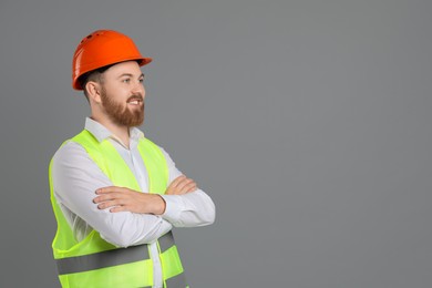 Engineer in hard hat on grey background, space for text