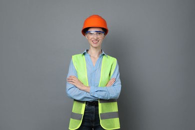 Photo of Engineer in hard hat and goggles on grey background