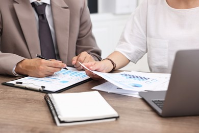 Photo of Consultant working with client at wooden table in office, closeup. Business meeting