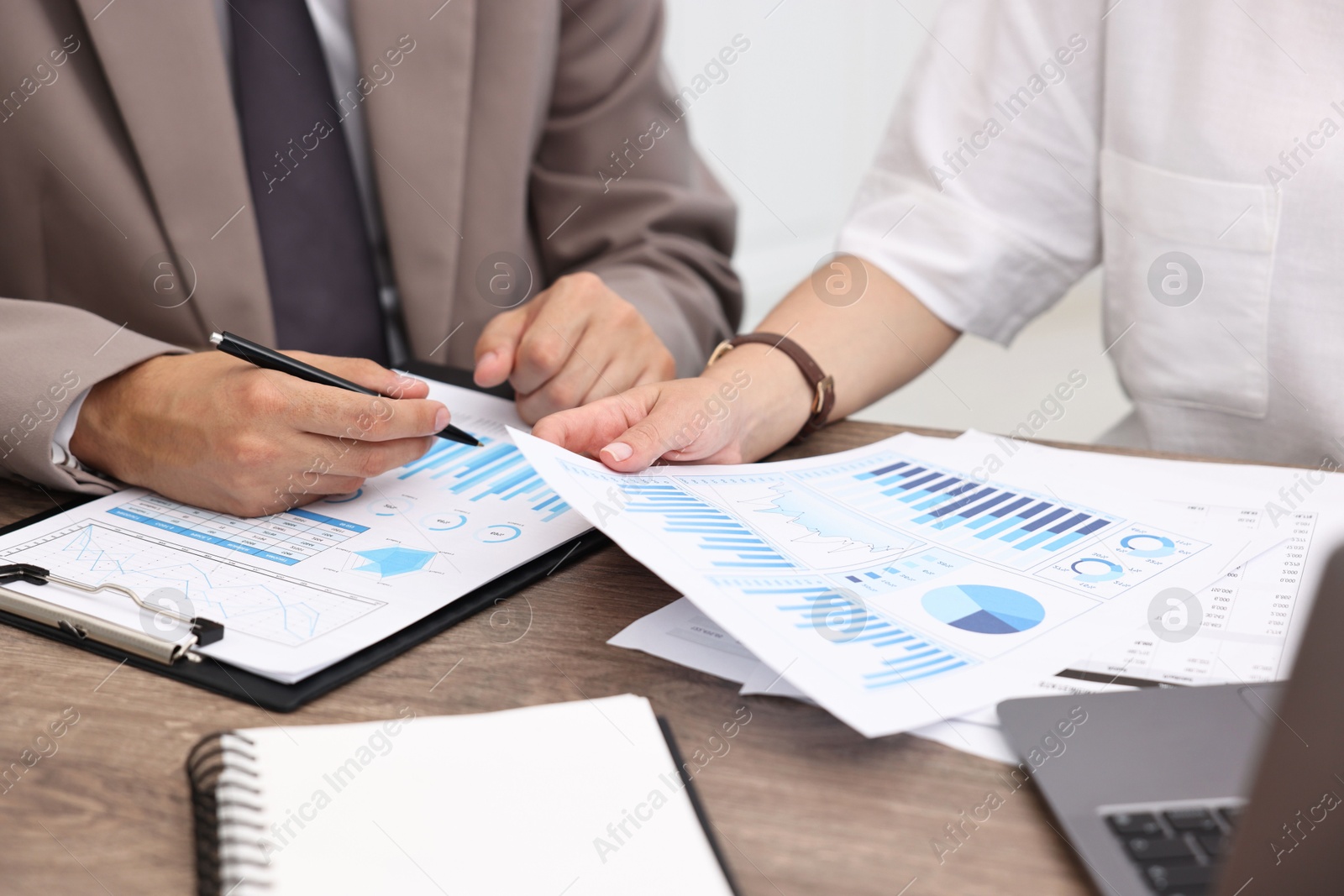 Photo of Consultant working with client at wooden table in office, closeup. Business meeting