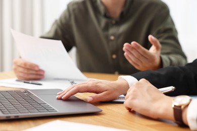 Photo of Consultant working with client at wooden table in office, closeup. Business meeting