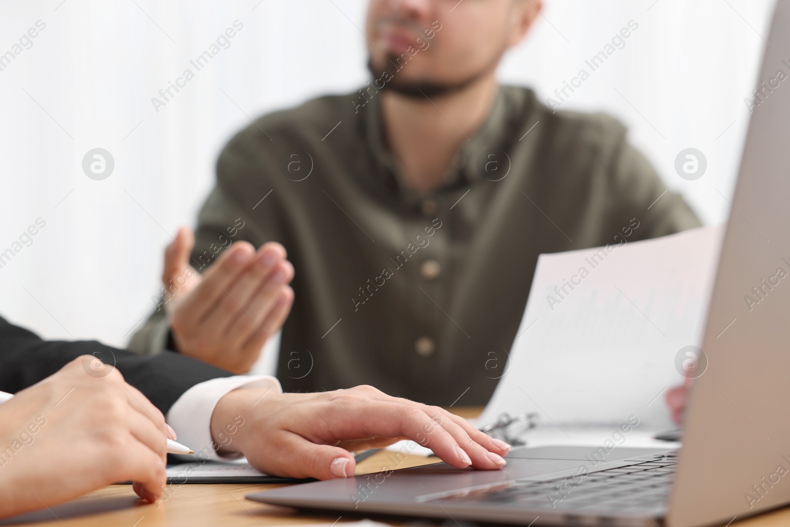 Photo of Consultant working with client at wooden table in office, closeup. Business meeting