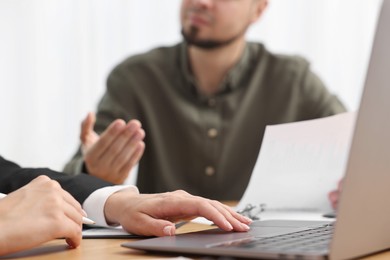 Consultant working with client at wooden table in office, closeup. Business meeting