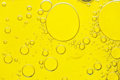 Photo of Sample of cosmetic oil on yellow background, macro view