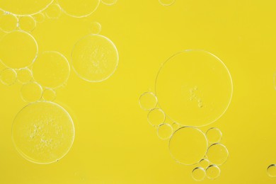 Photo of Sample of cosmetic oil on yellow background, macro view