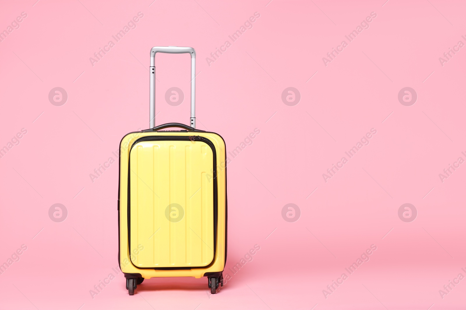 Photo of One new yellow suitcase on pink background, space for text