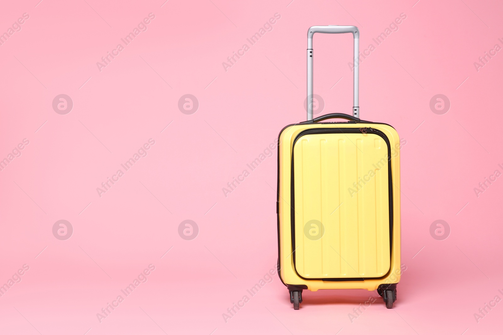 Photo of One new yellow suitcase on pink background, space for text