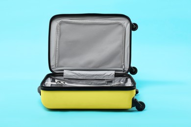 Open empty suitcase on light blue background