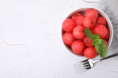 Photo of Tasty watermelon balls with mint in bowl served on white textured table, flat lay. Space for text