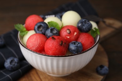 Photo of Tasty watermelon and melon balls with blueberries in bowl on table, closeup