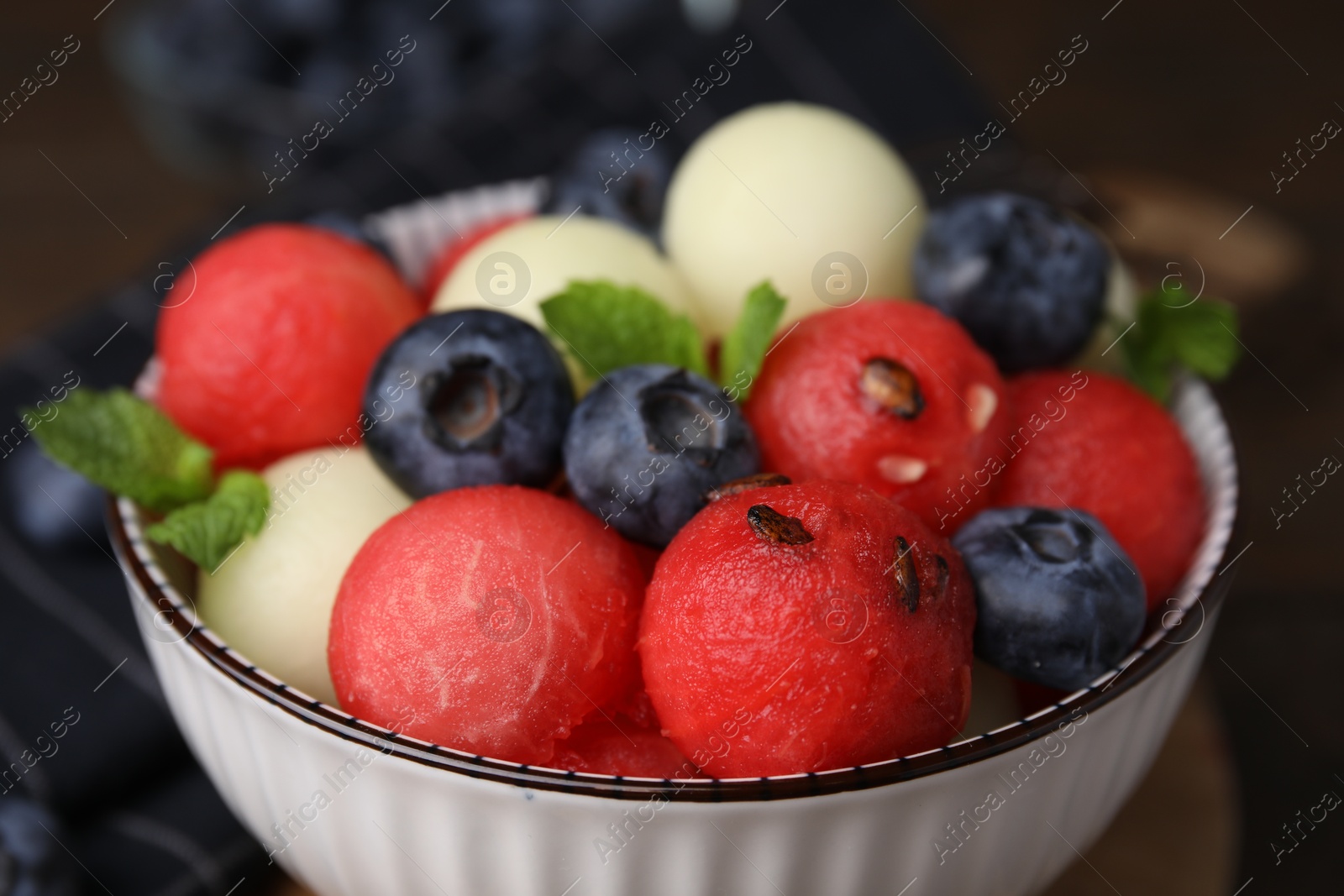 Photo of Tasty watermelon and melon balls with blueberries in bowl on table, closeup