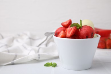 Photo of Tasty watermelon and melon balls with strawberries in bowl on white tiled table, closeup. Space for text